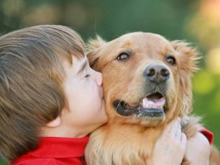 Young boy shows compassion for his dog with a big kiss
